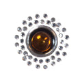 Applikation mit bernsteinfarbenem Glasstein, umringt von silbernen Kristallsteinen im Kreis