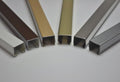 Sechs U-Profile in Reihe: braun, gold, champagner, silber und chrom, glaenzende Metalloberflaeche