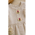 Beiges Kinder Leinenkleid mit Holzknöpfen und Schmetterling Motiv in Nahaufnahme