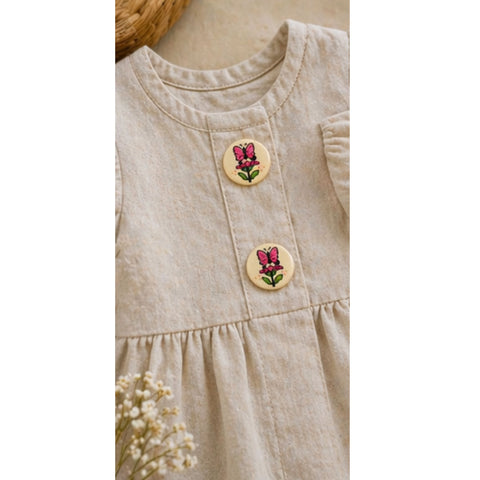 Beiges Kinder Leinenkleid mit Holzknöpfen und Schmetterling Motiv in Nahaufnahme